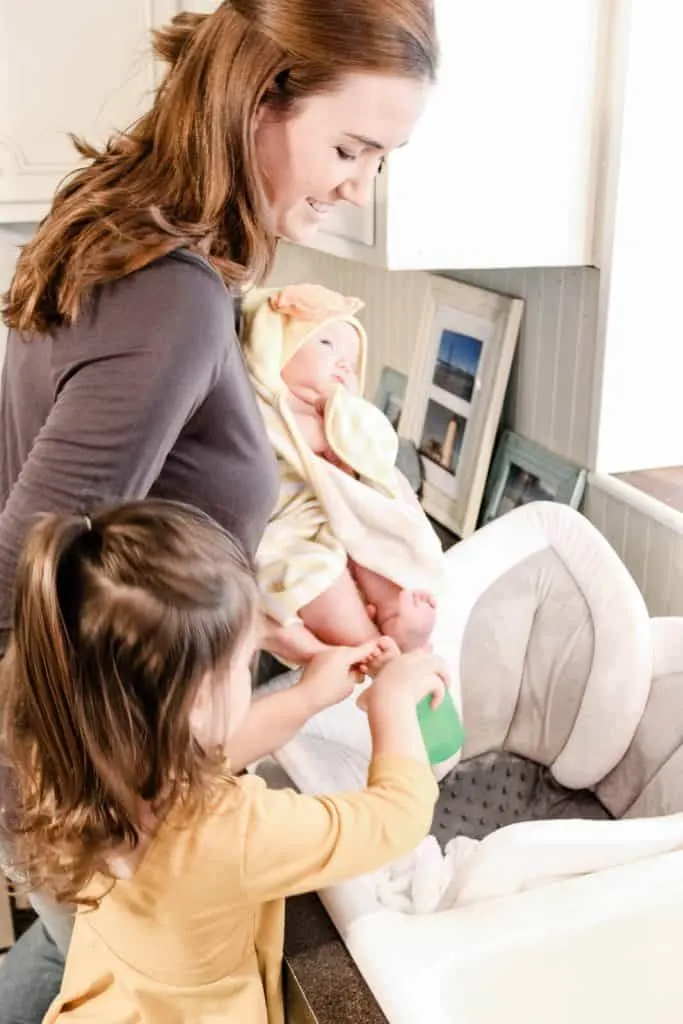 Woman and toddler prepare baby for first bath.