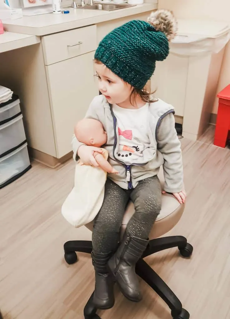 Toddler girl with doll in a pediatrician's office.