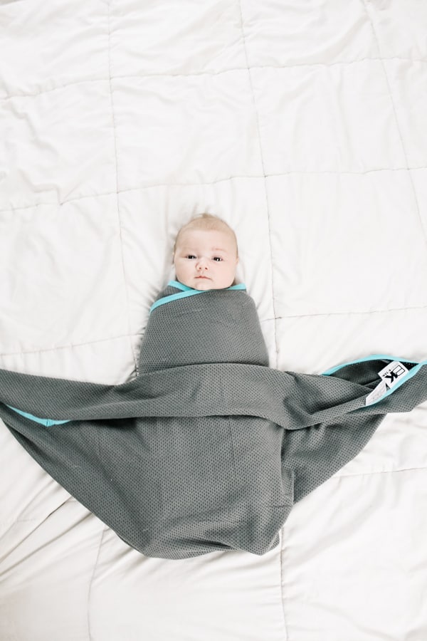 final step of how to to a boat swaddle on a baby: tuck in the extra corners