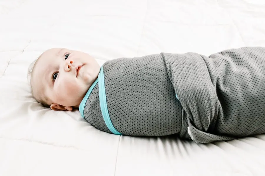 Newborn in grey and teal swaddle.