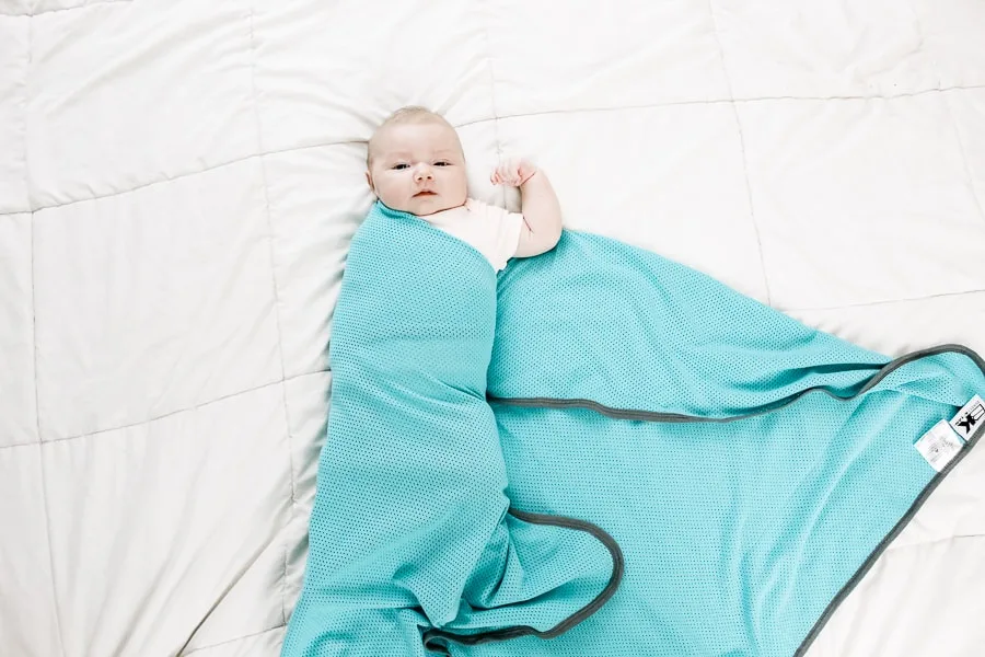 step 3 of how to swaddle a baby: fold the swaddle blanket over the baby