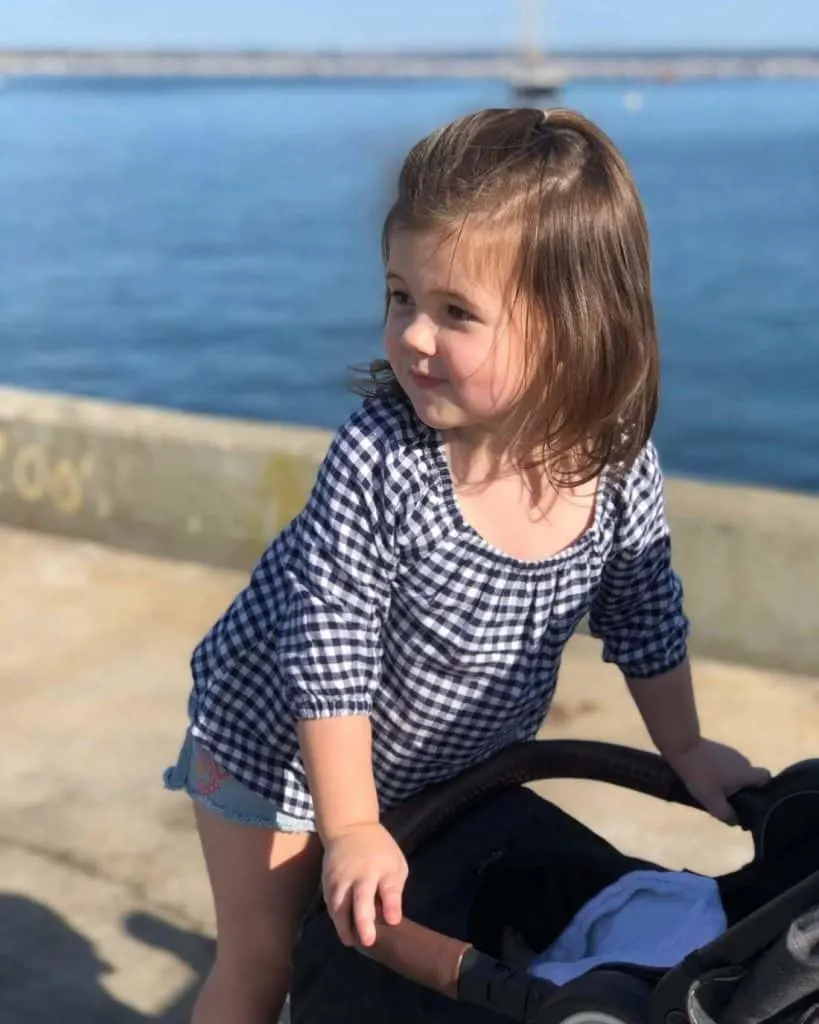 Girl plays on dock next to water in Massachusetts. 