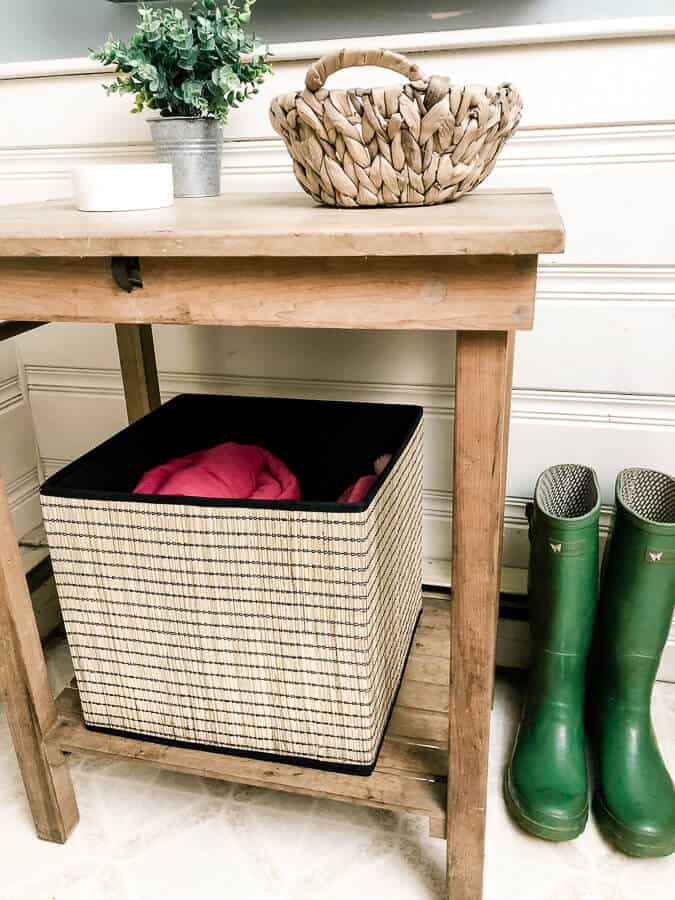 Front entry table with baskets next to green boots.