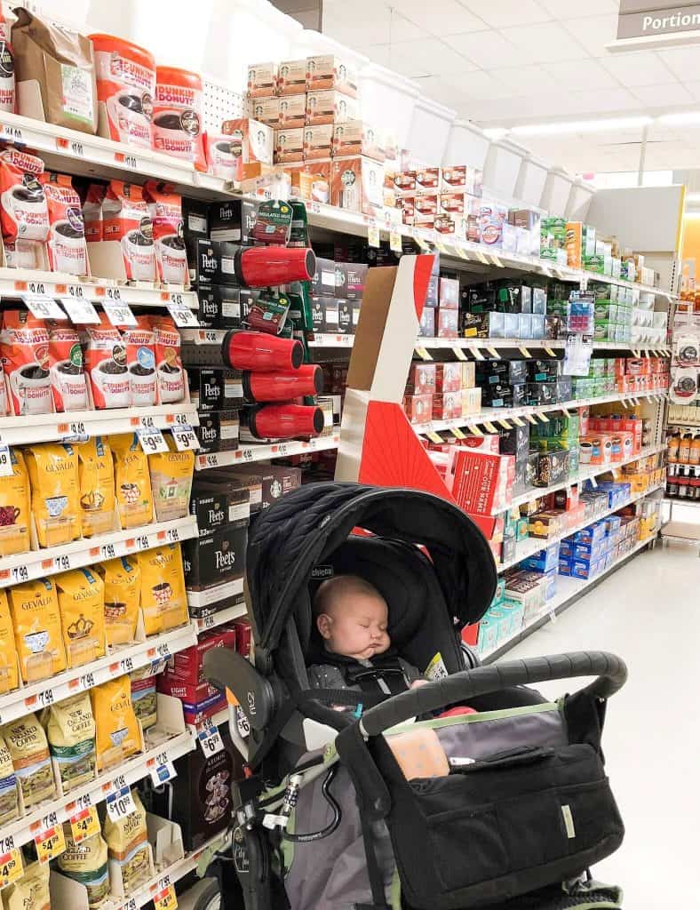 Baby sits in stroller in grocery aisle.