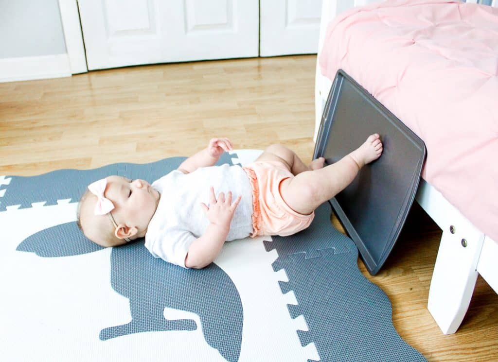 Baby uses feet to play with sheet pan.
