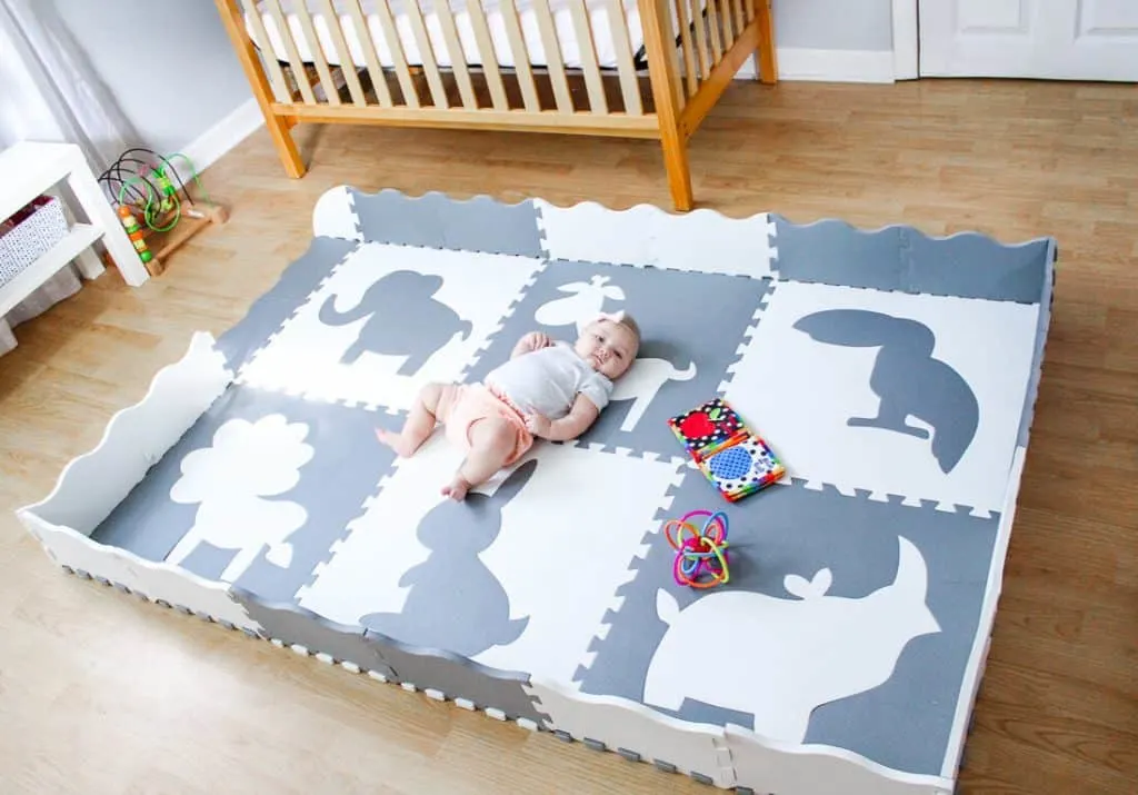 Baby does activities on play mat in nusery.