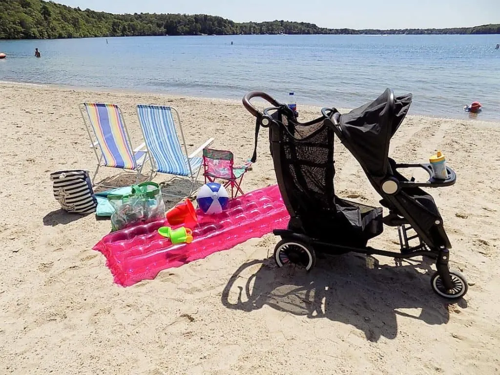Stroller on beach next to chairs and float.