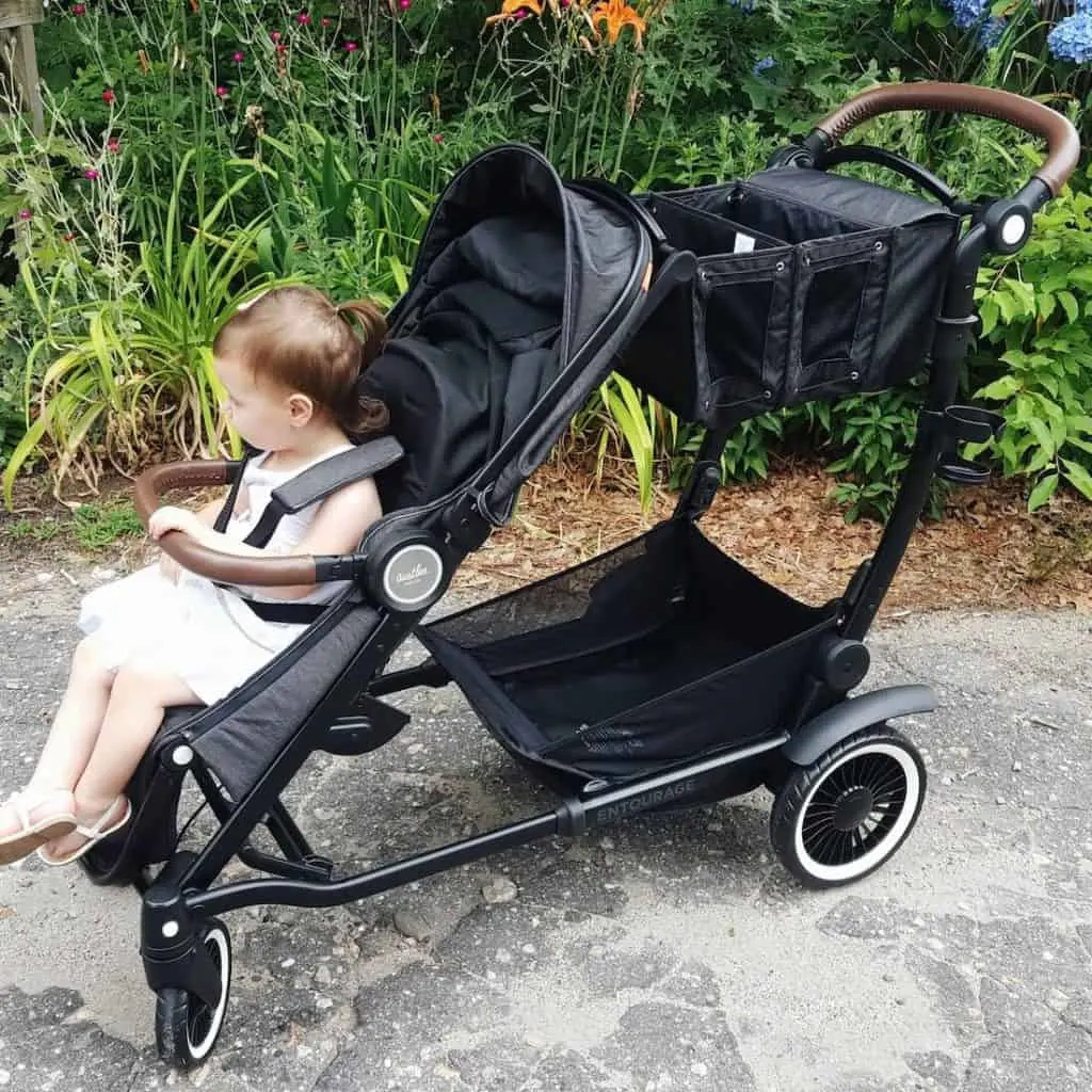 Child sits in double stroller at Disney park.