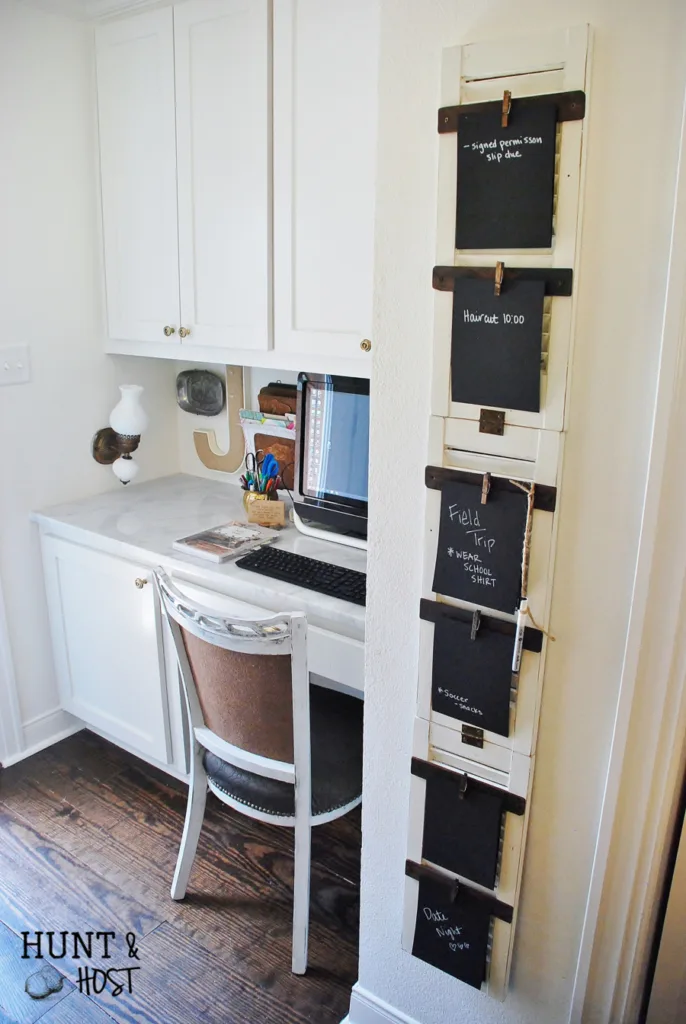 A to-do-list chalkboard organizer on upcycled shutters next to a built-in desk with cabinets above it.