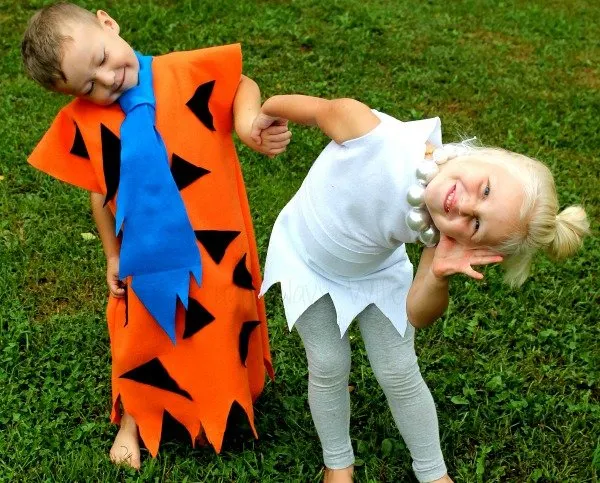 Boy and girl siblings dressed up as Fred and Wilma from the Flintstones.