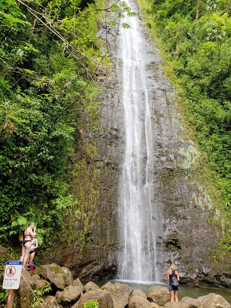 People stand under waterfall in Oahu.