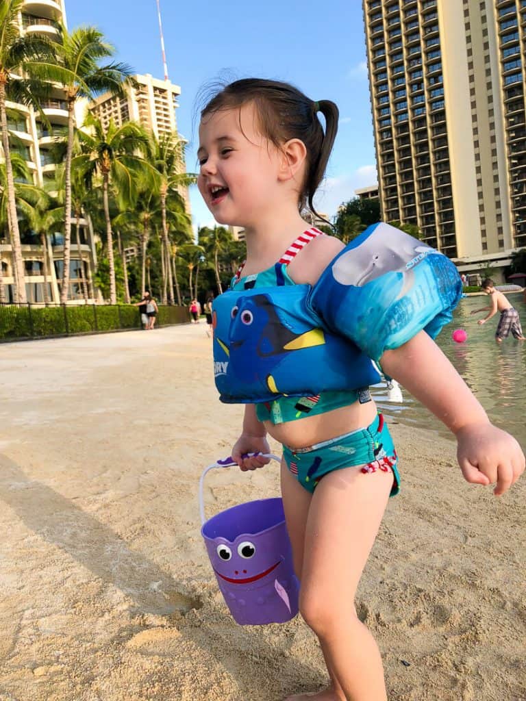 Girl plays on beach next to Hawaii hotel.
