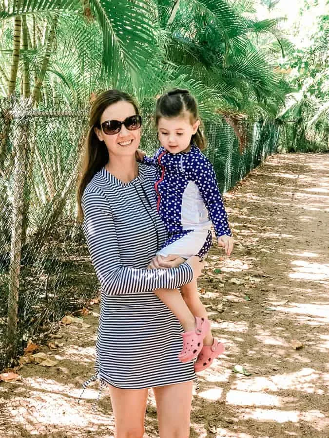 Mother holds toddler girl on hidden Hawaiian beach.