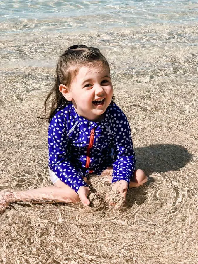 Little girl plays in water at beach.