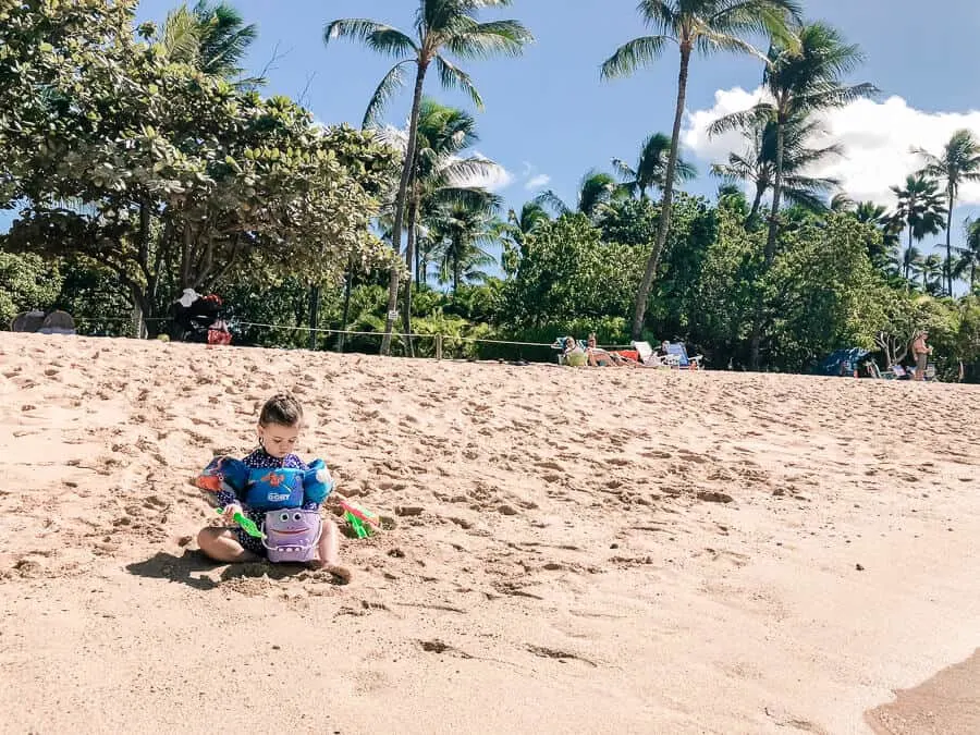 Girl plays in the sand at Family beach in Oahu.