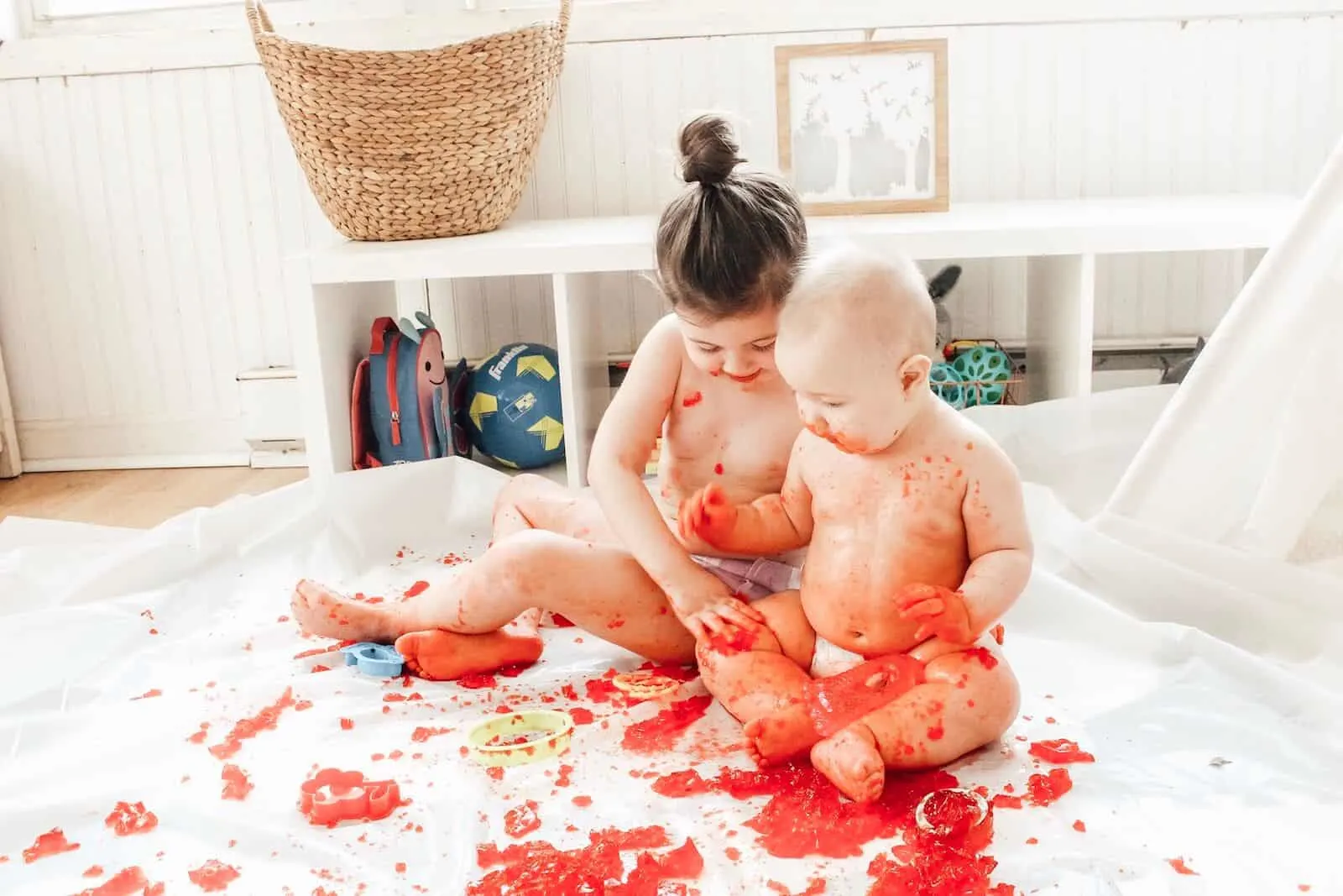 Baby and toddler making a mess with jello during sensory play