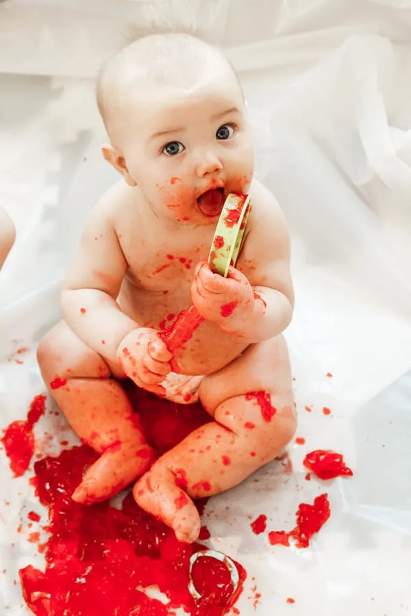 Baby eats and plays with red Jello.
