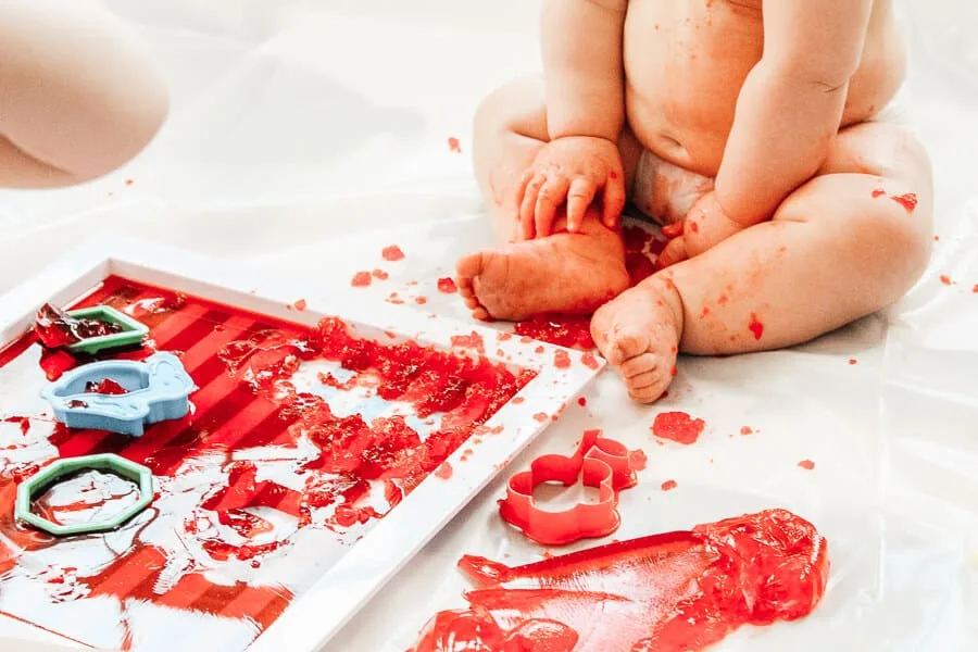 Baby mashes Jello for sensory play.