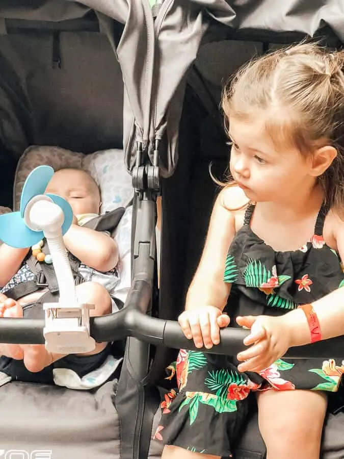 Toddler and baby in double stroller at Disney park.