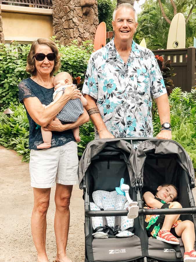 Family pushes double stroller at tropical Disney resort.