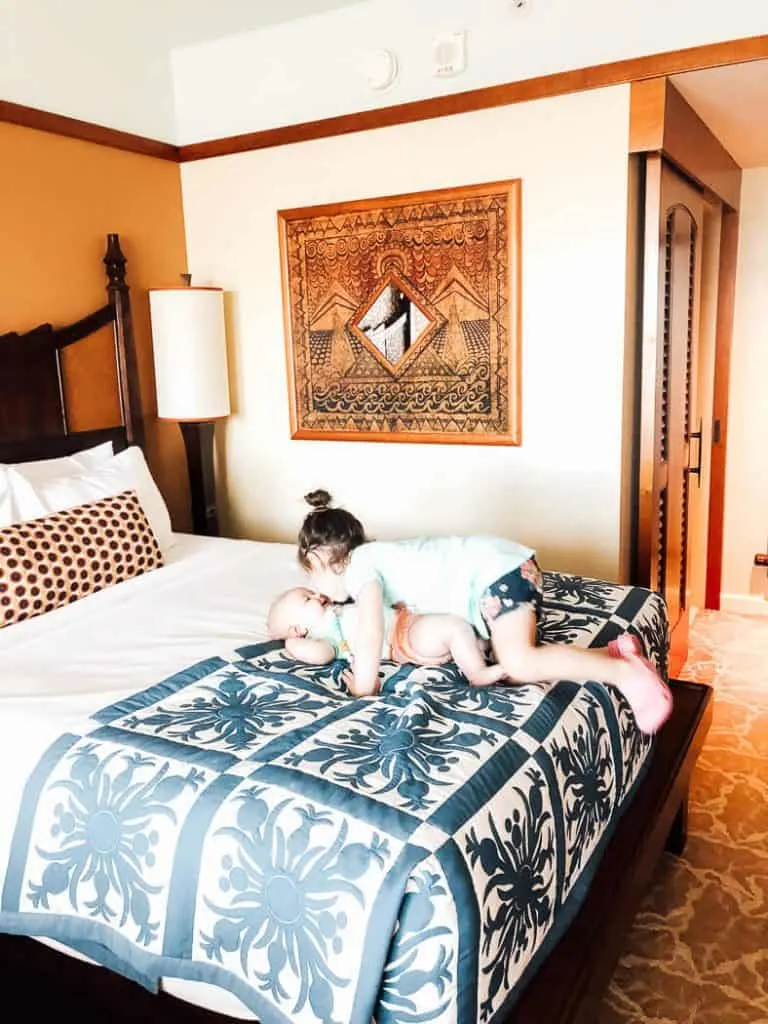 Young girls play on bed at Disney\'s Aulani Resort.