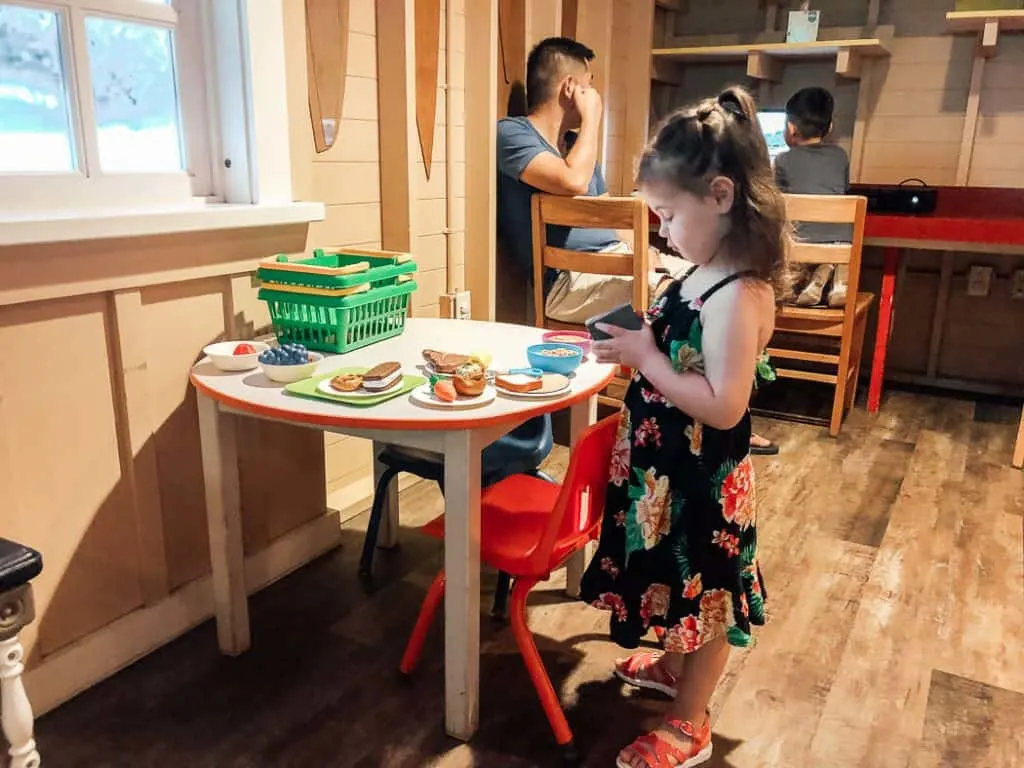 Little girl plays with pretend food at Disney resort.