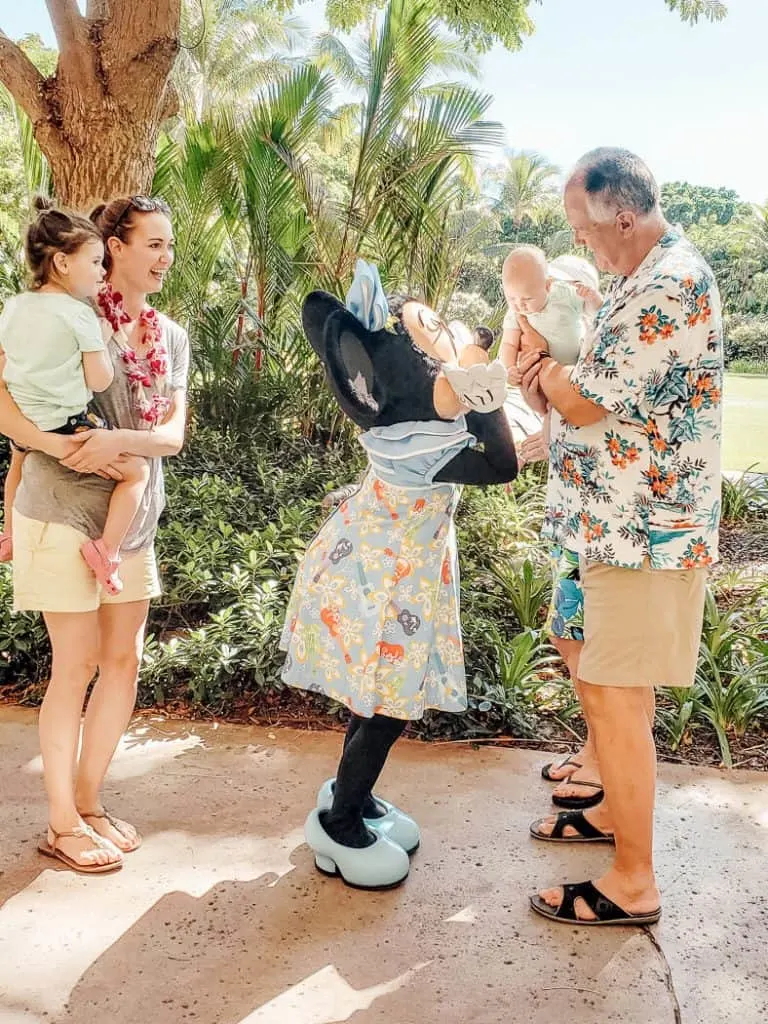 Family interacts with Mini Mouse at Disney park.