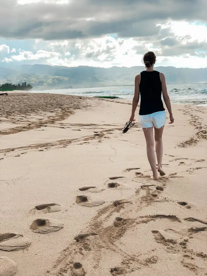 Woman walks on beach in Oahu Hawaii.