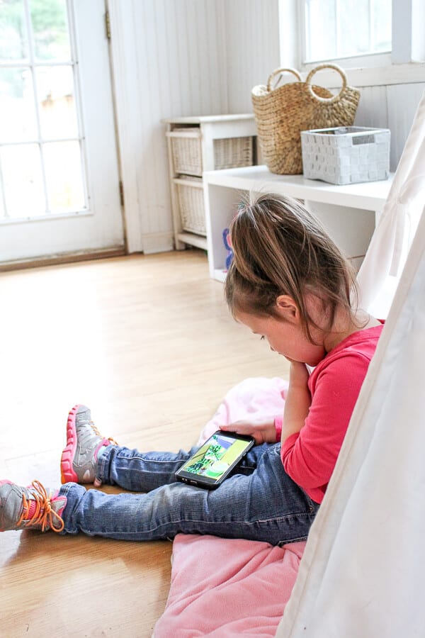Girl plays on tablet in playroom.