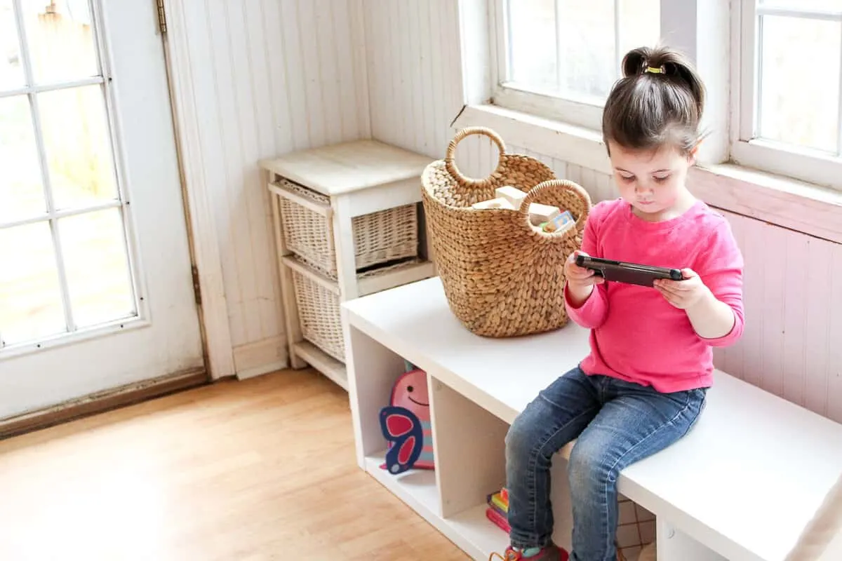 Girl plays on digital device in playroom.