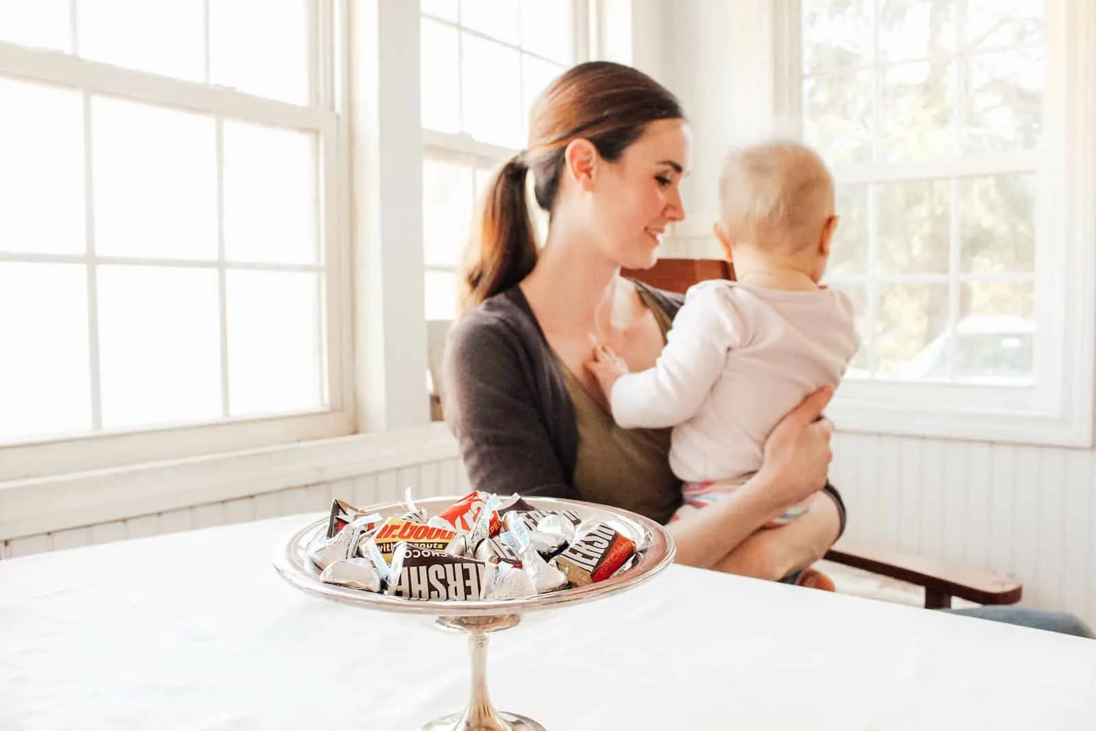 New Mom holds baby next to tray of chocolates.