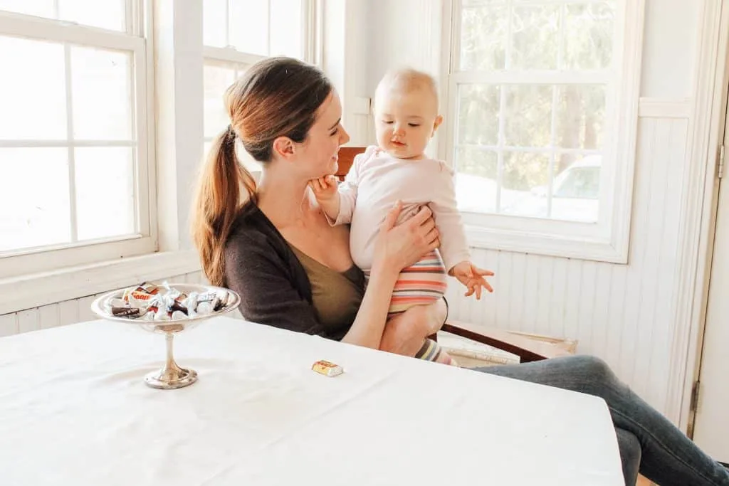 New mother holds baby in dining room.