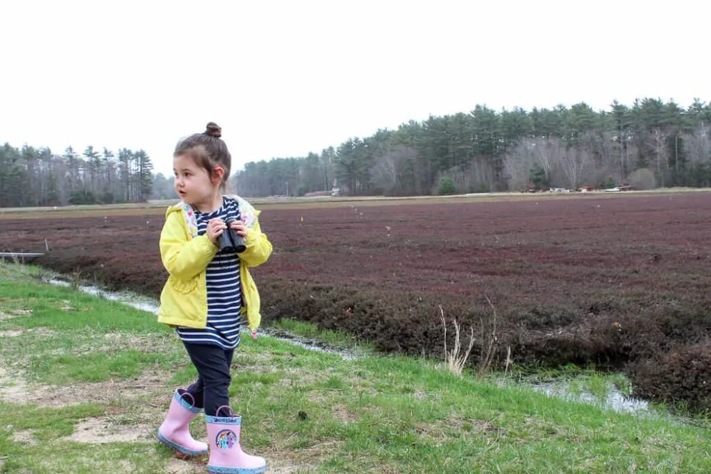 Girl in rain boots plays outside.