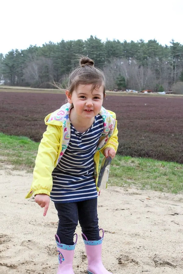 Girl plays outside next to field.