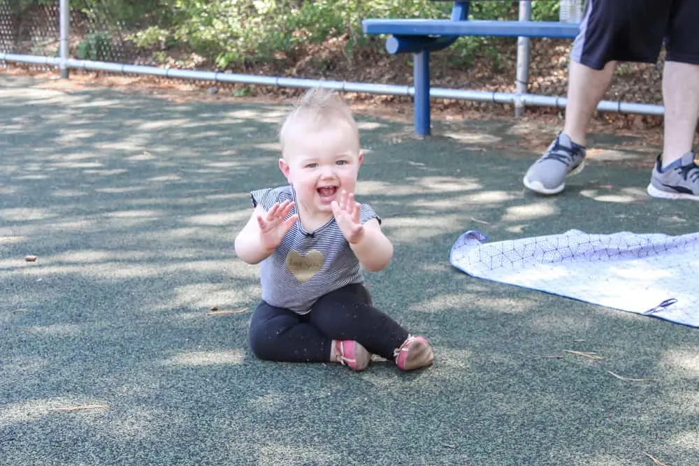 Baby plays on ground of play park.