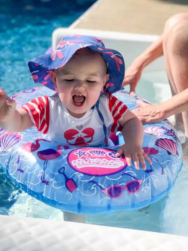 Baby splashing in pool with float