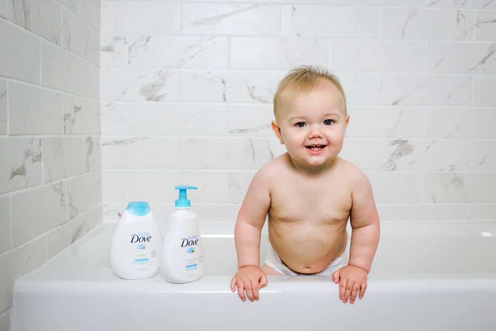Baby standing in a bathtub with Baby Dove Rich Moisture Tip to Toe Wash and Rich Moisture Lotion
