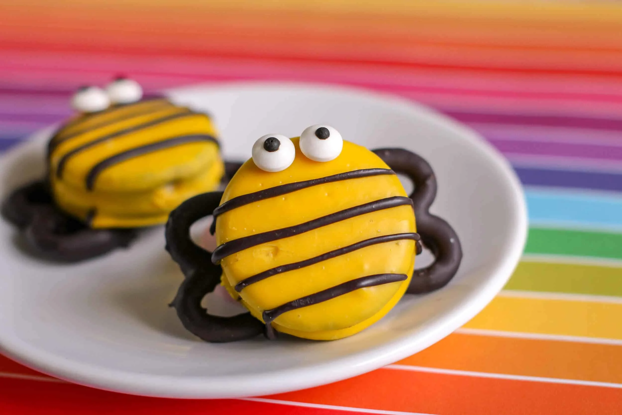 DIY bee decorated cookies on white plate.