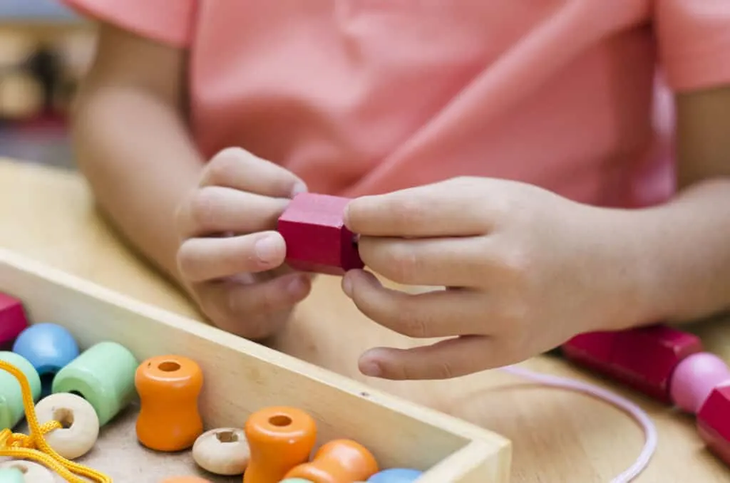 child threading beads in montessori play
