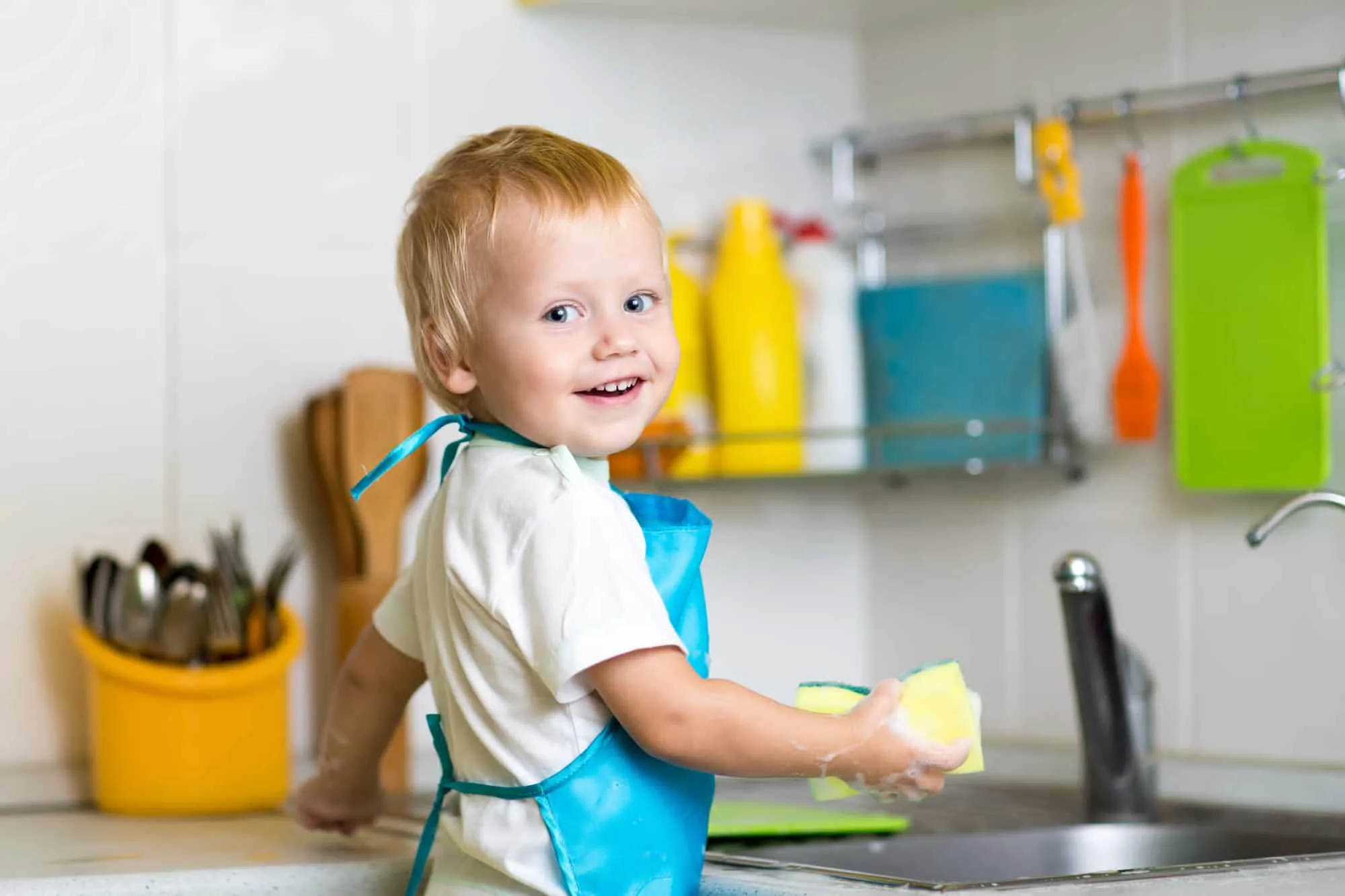 Toddler standing a sink doing montessori practical life activties