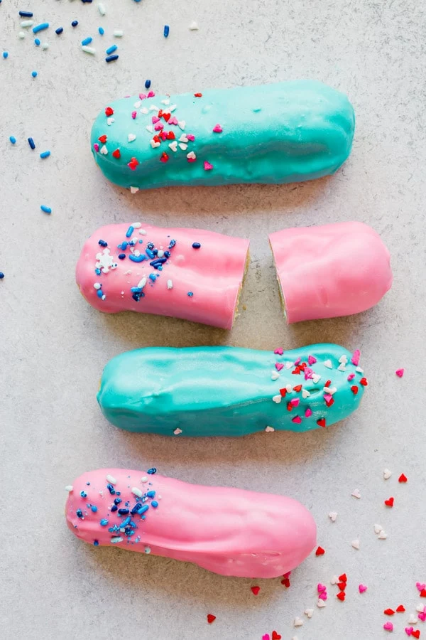 Homemade eclairs with pink and blue icing and sprinkles.