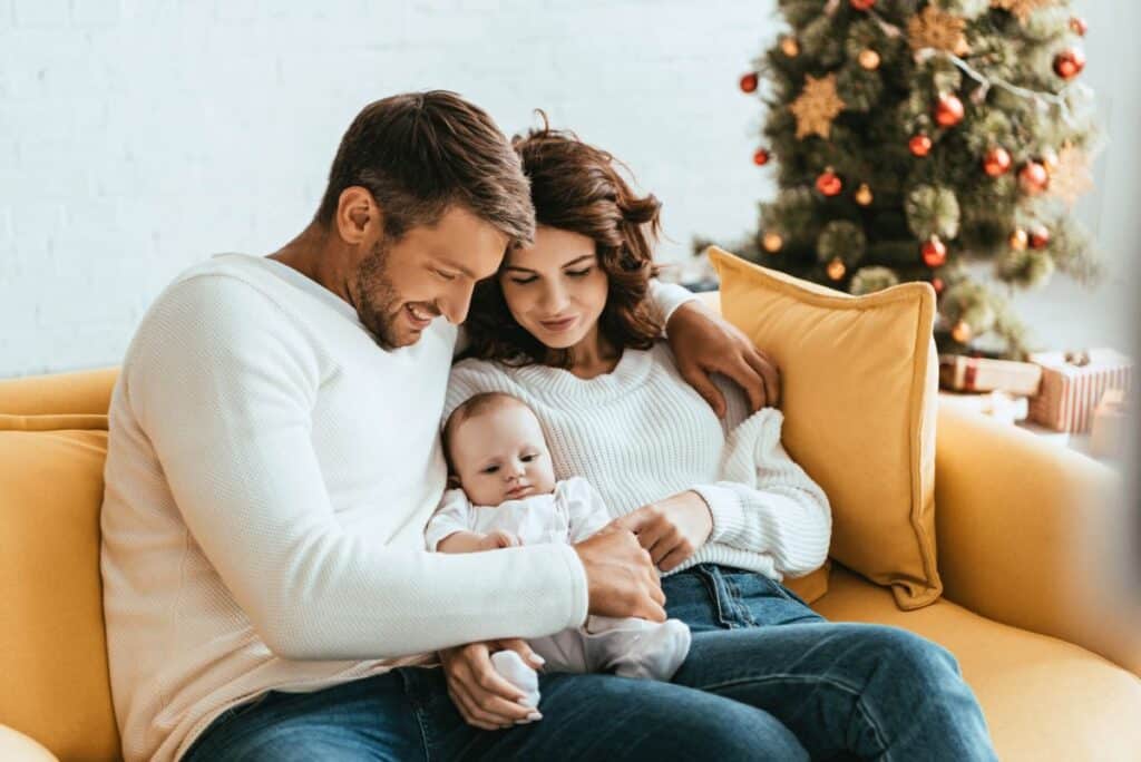 New parents with baby in front of Christmas tree