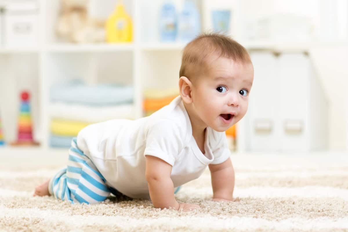 baby crawling in front of montessori toy shelf