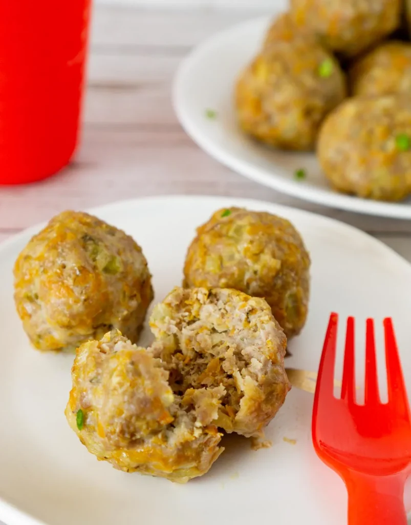 Meatballs on a white plate with a red fork.