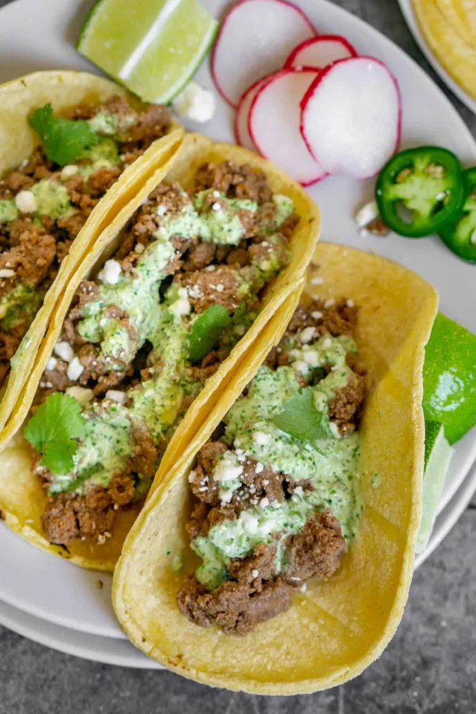 Venison tacos with green taco sauce and cilantro.