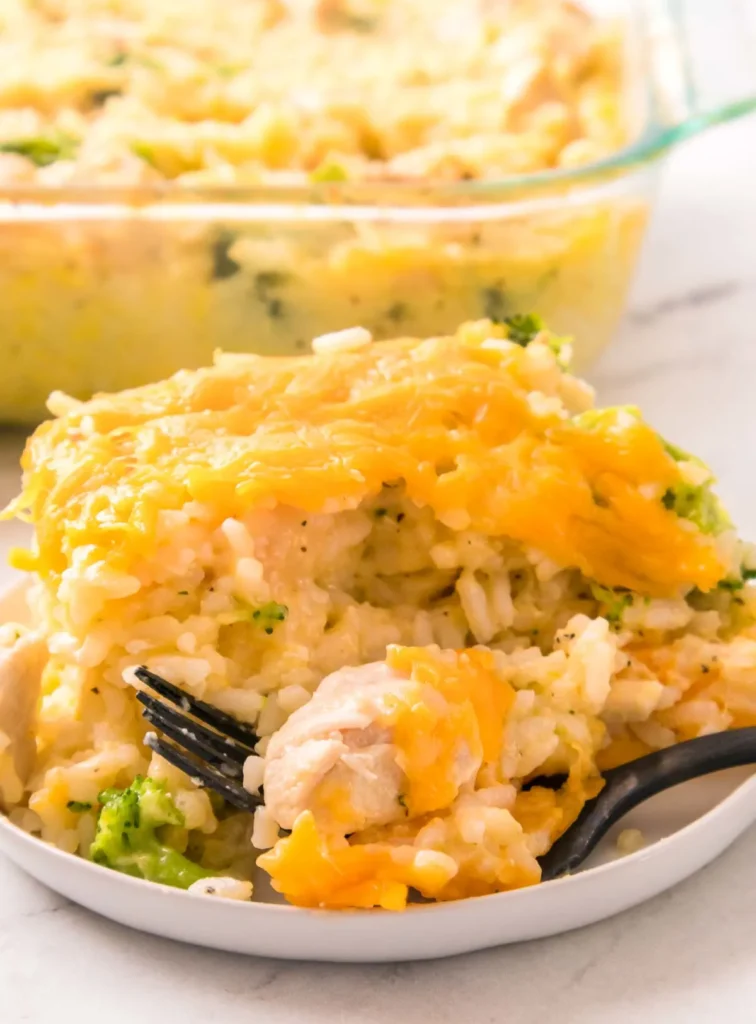 Chicken and broccoli casserole on a white plate and in a casserole dish in the background.