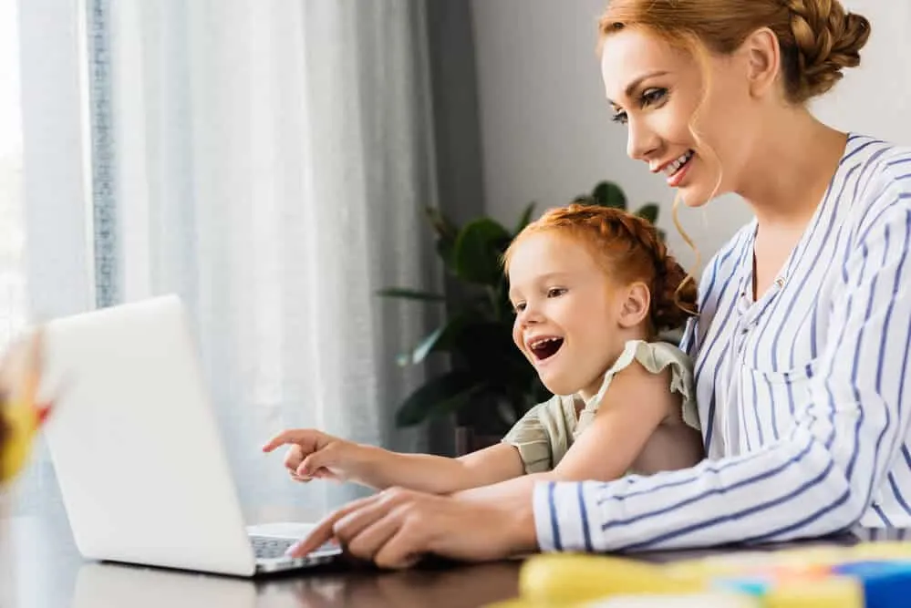 Woman and child use computer for a virtual birthday celebration at home.