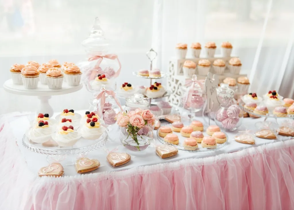 A table with a pink tulle tablecloth and sweets.