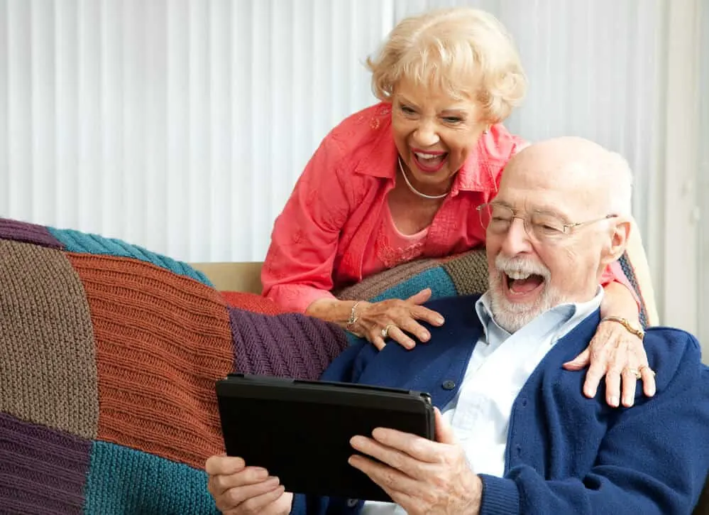 Grandparents excited using a tablet.