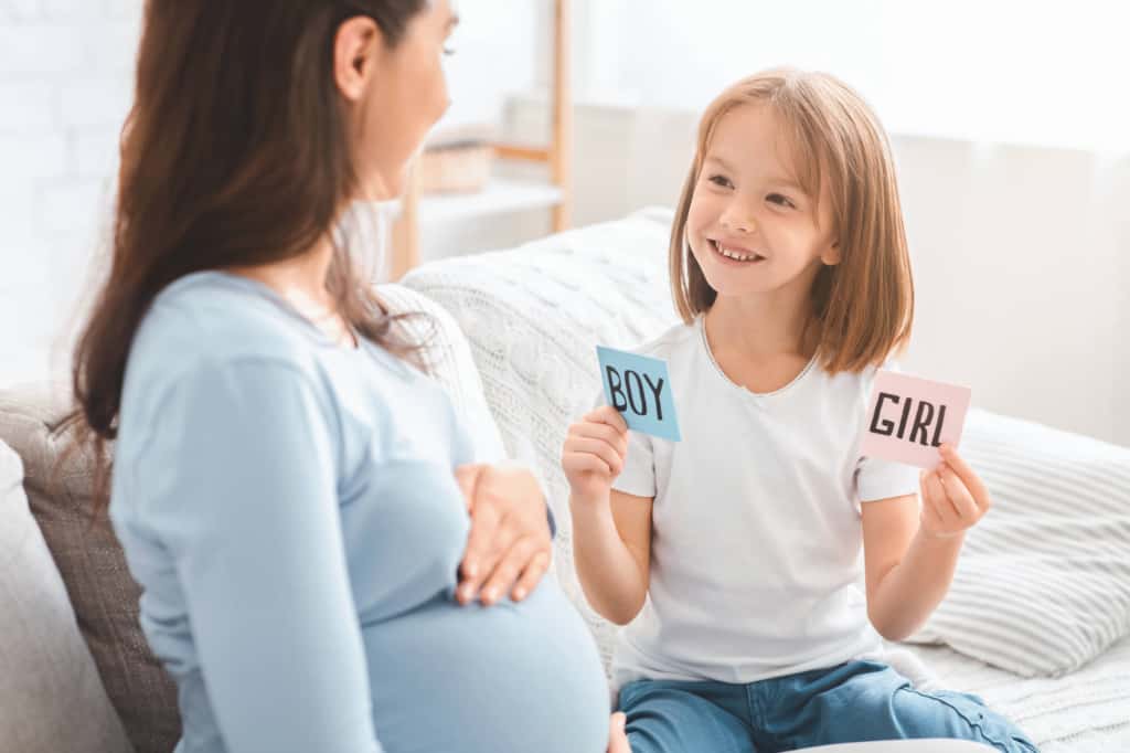 pregnant woman with daughter holding boy and girl cards
